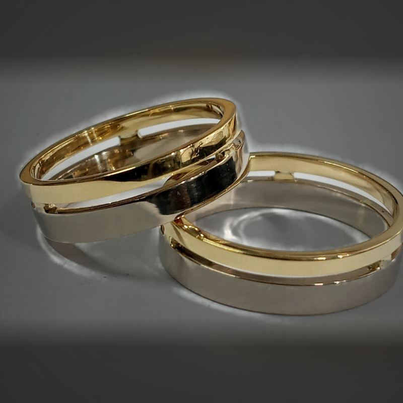 Alianças bicolores em ouro amarelo e branco com design vazado e entrelaçado