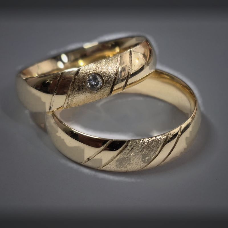 Alianças personalizadas em ouro com cortes diagonais, faixa fosca e solitário