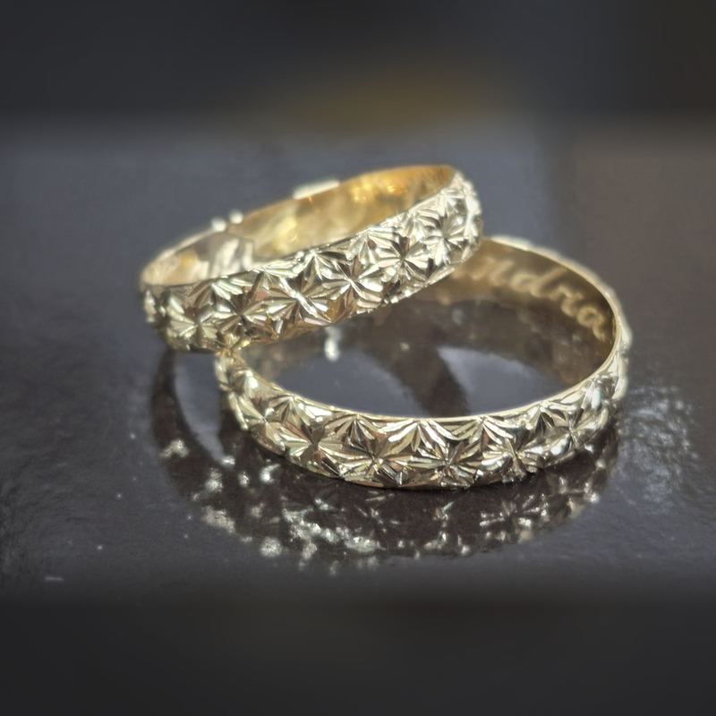 Par de alianças em ouro com acabamento diamantado em estrelas e gravação interna
